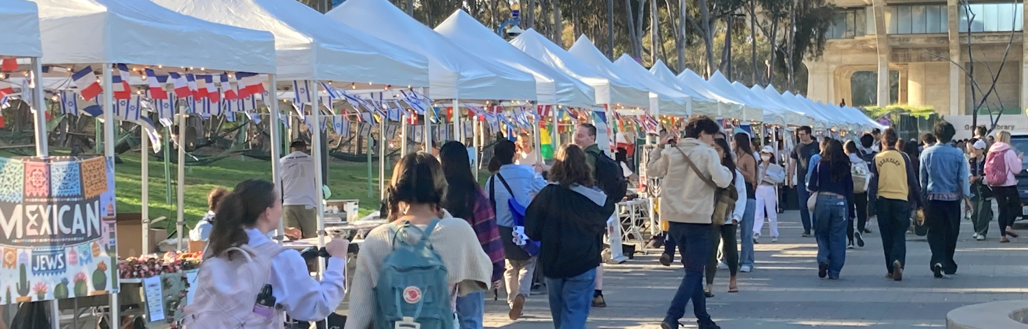 white tents with flags students walking