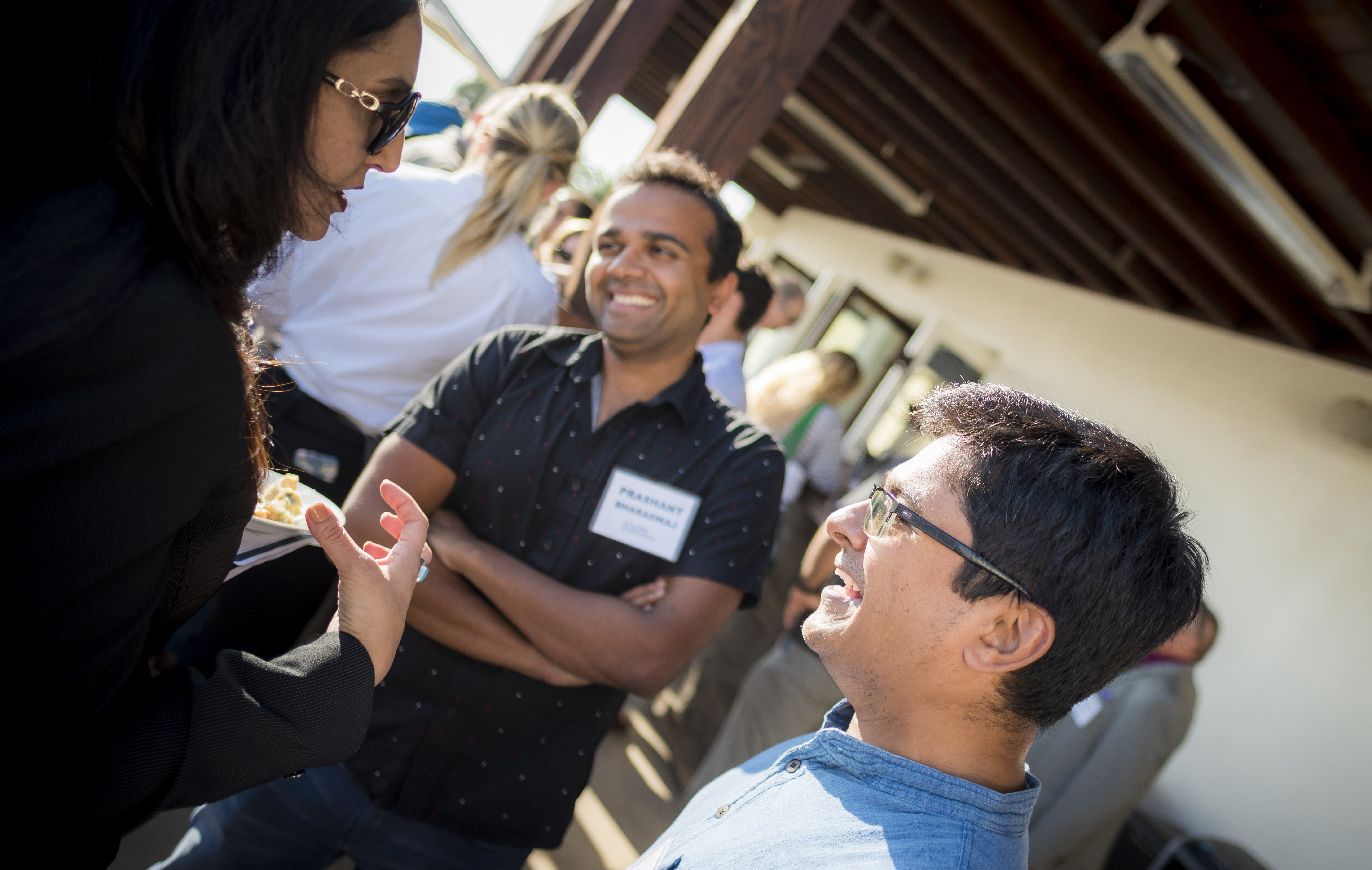 three faculty members talking to each other. the one directly in front of the camera is laughing, the two others are in profile