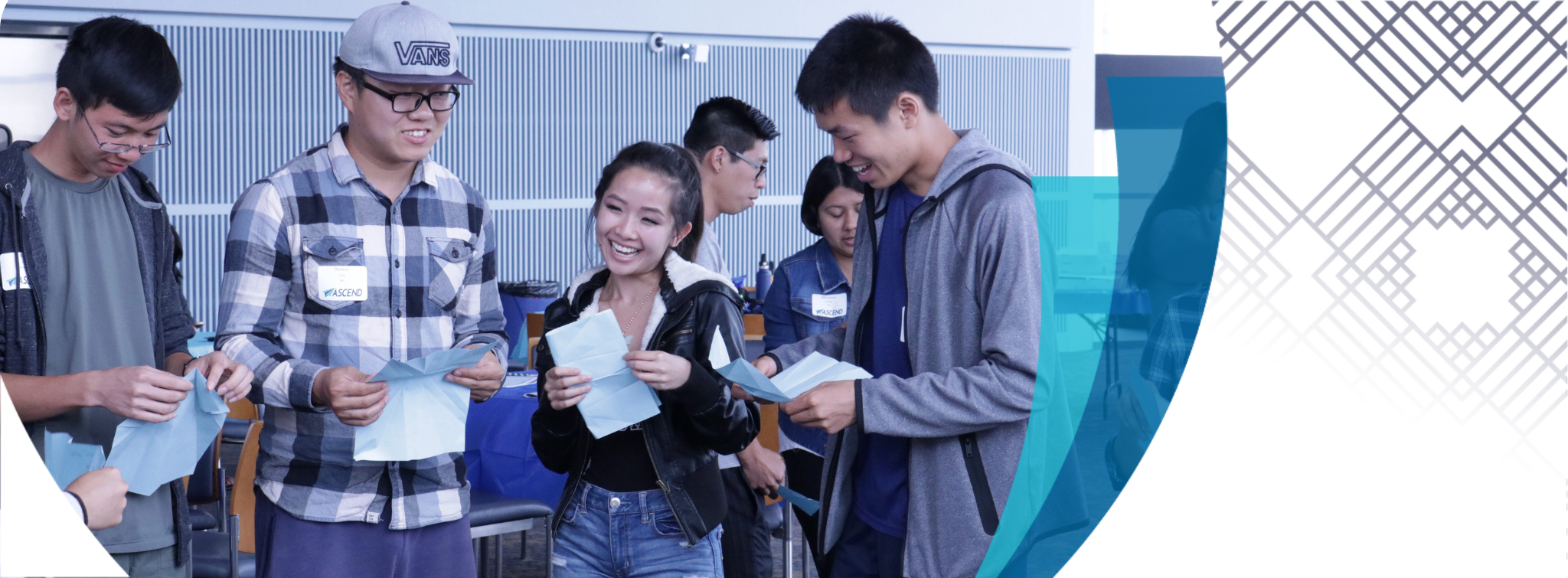 2 of 5, Four students are smiling and holding papers they have unfolded